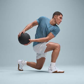 Atleta en gimnasio realizando sentadilla con barra y ropa técnica Under Armour